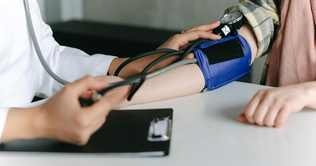 Adult having blood pressure measured, representing routine blood pressure check frequency guidelines